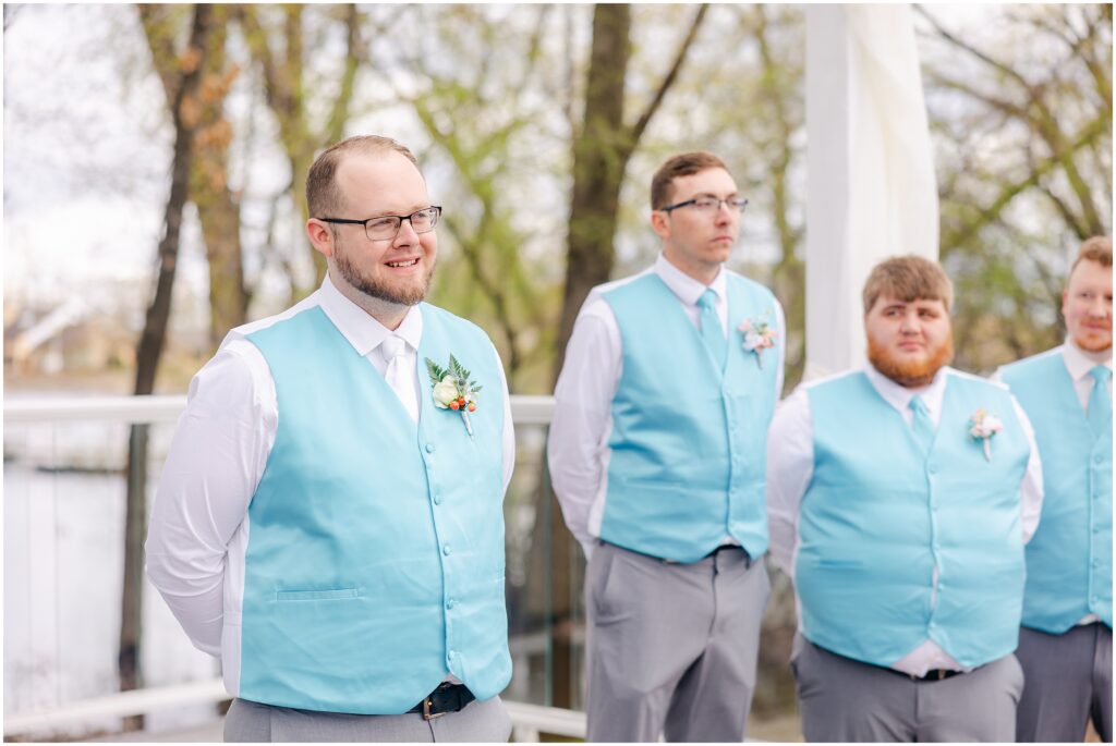 Photo of groom and groomsmen looking at the bride walking down the aisle.
