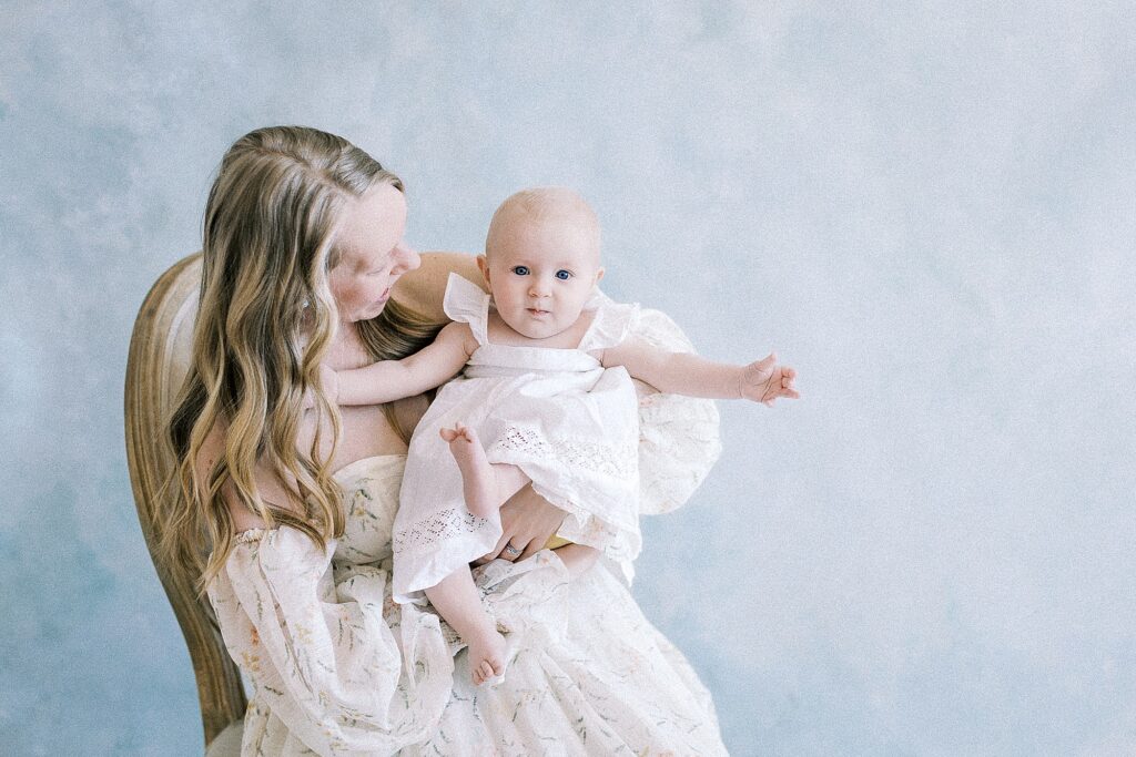 Smiling mother and baby girl in soft neutral gowns during La Crosse motherhood photography session
