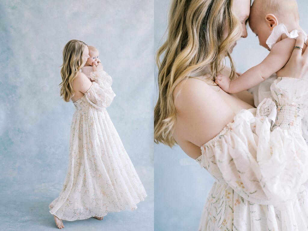 Mother holding baby in flowing gown against hand painted backdrop in La Crosse photography studio